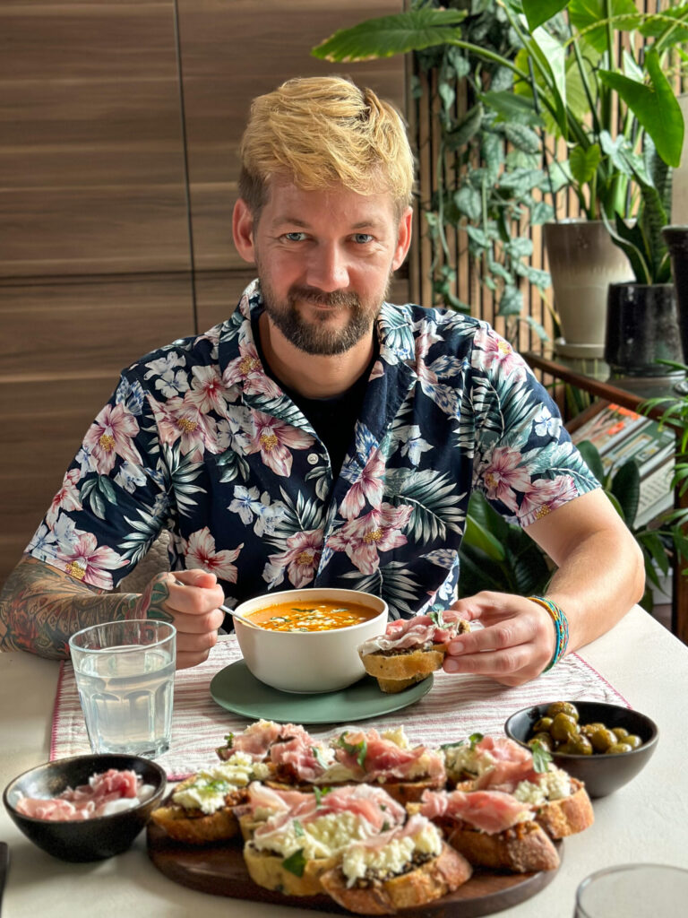 Jan Willem eet verse tomatensoep aan tafel met rijkelijk belegd stokbrood