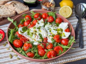 Salade caprese met burrata, geroosterde tomaten, rucola en basilicumolie