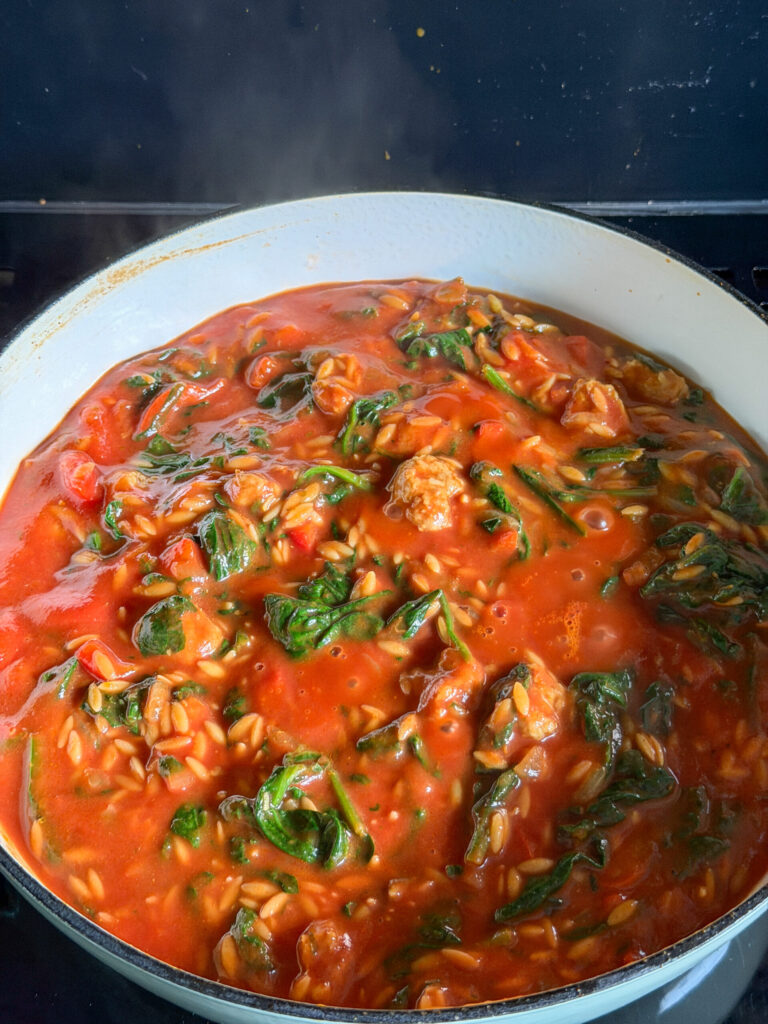 orzo garen in tomatensaus van gezeefde tomaten en bouillon