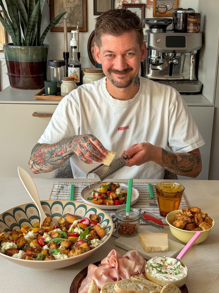 Jan Willem raspt Parmezaanse kaas over een bruschetta salade met mozzarella