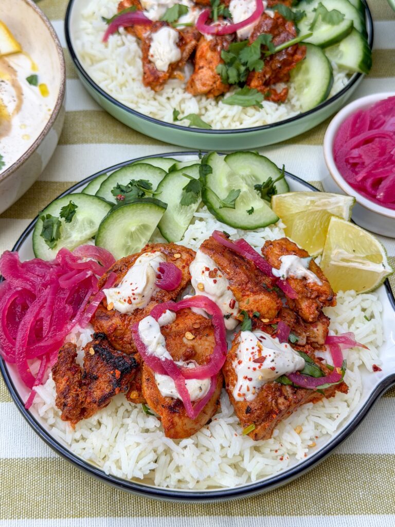 harissa kip met rijst, tahin yoghurt dressing, ingelegde rode ui en komkommer