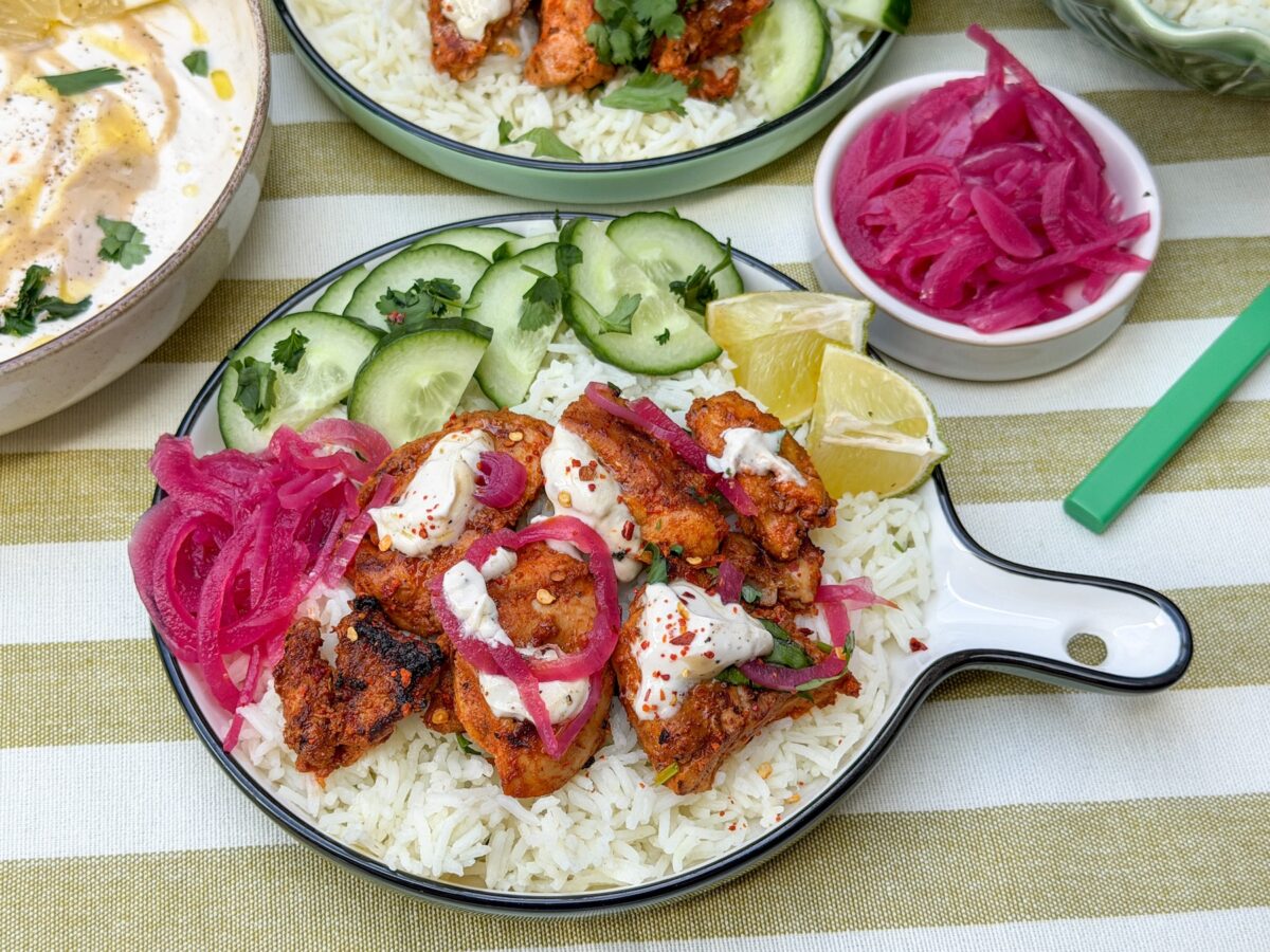 harissa kip met rijst, tahin yoghurt dressing, ingelegde rode ui en komkommer
