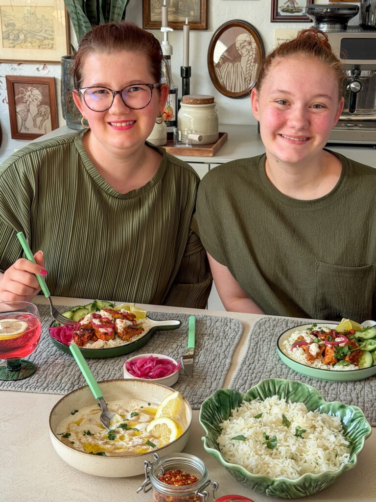 Beaudine en Amaranthe eten harissa kip met rijst en tahin yoghurtdressing aan tafel