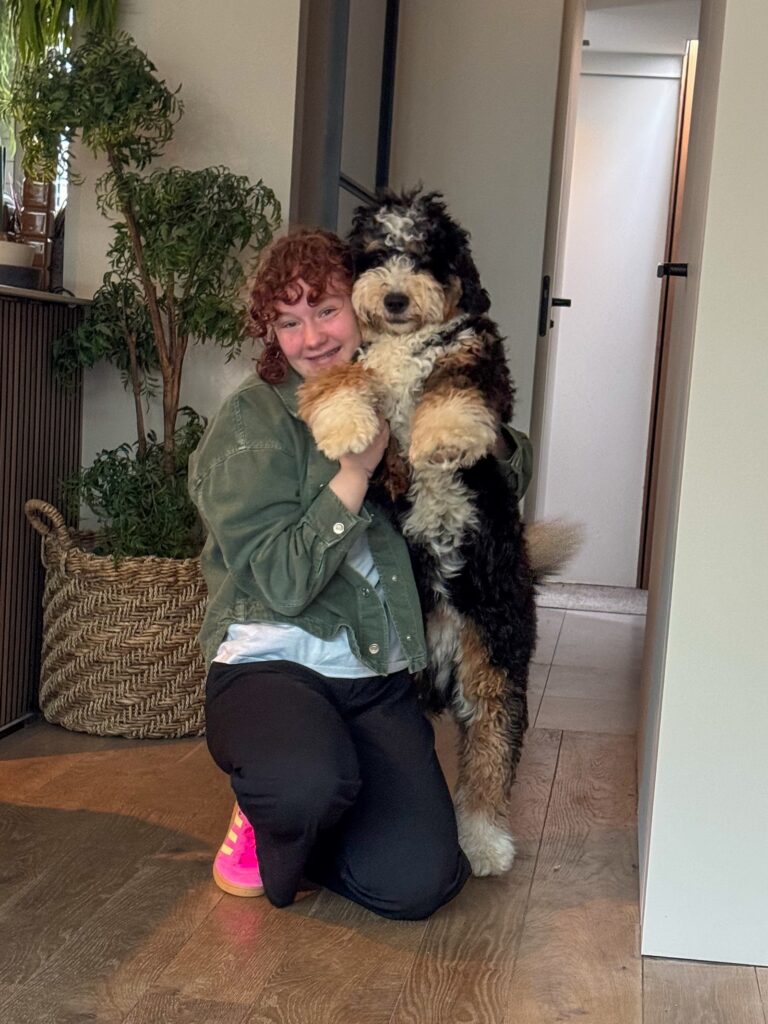 Amaranthe knuffelt bernedoodle in de woonkamer