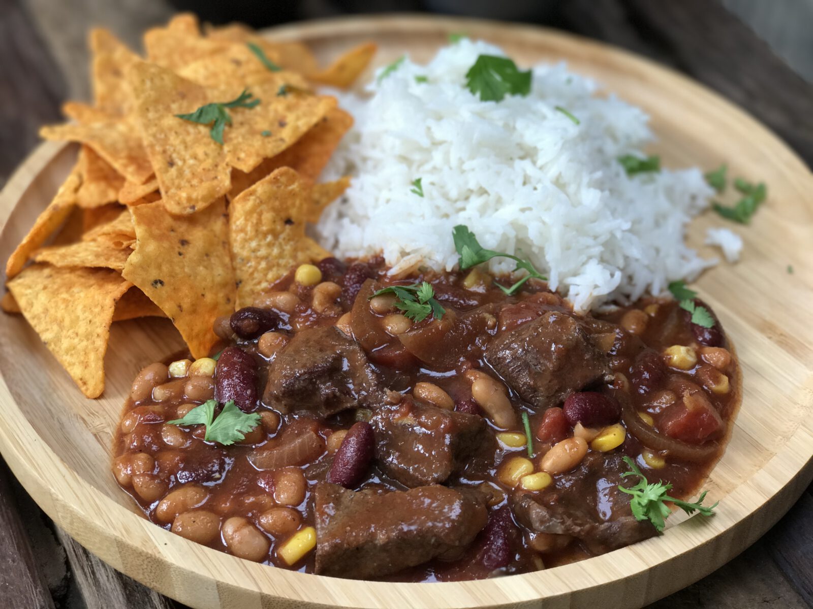 Chili con carne met stoofvlees geserveerd met bonen, mais en rijst