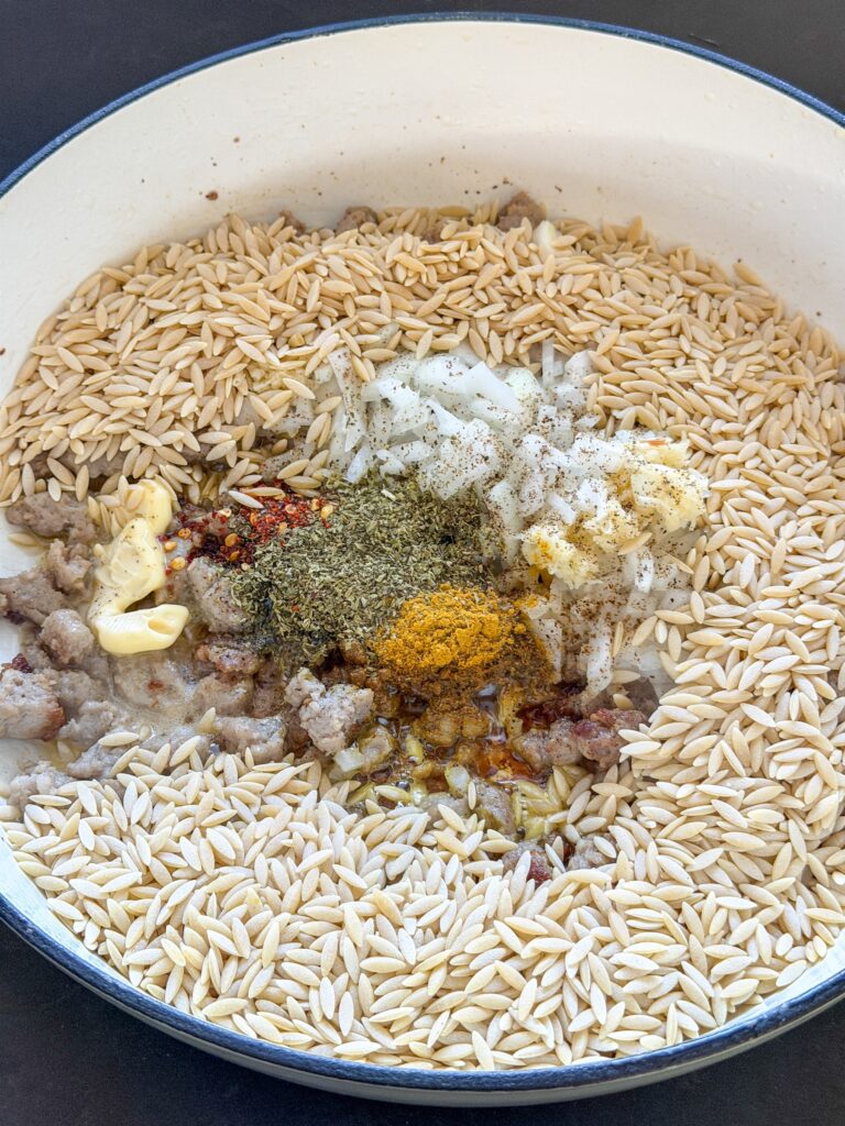 orzo met kruiden, ui en worst in pan bakken
