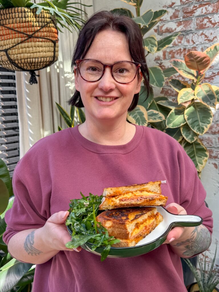 Marie Louise serveert een tosti met pesto arrabbiata en mortadella