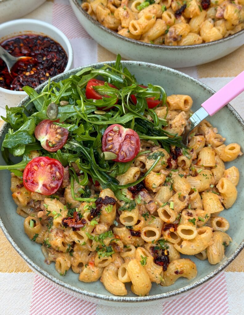 Pasta roomsaus met crispy chili olie, spek en rucola salade in kom