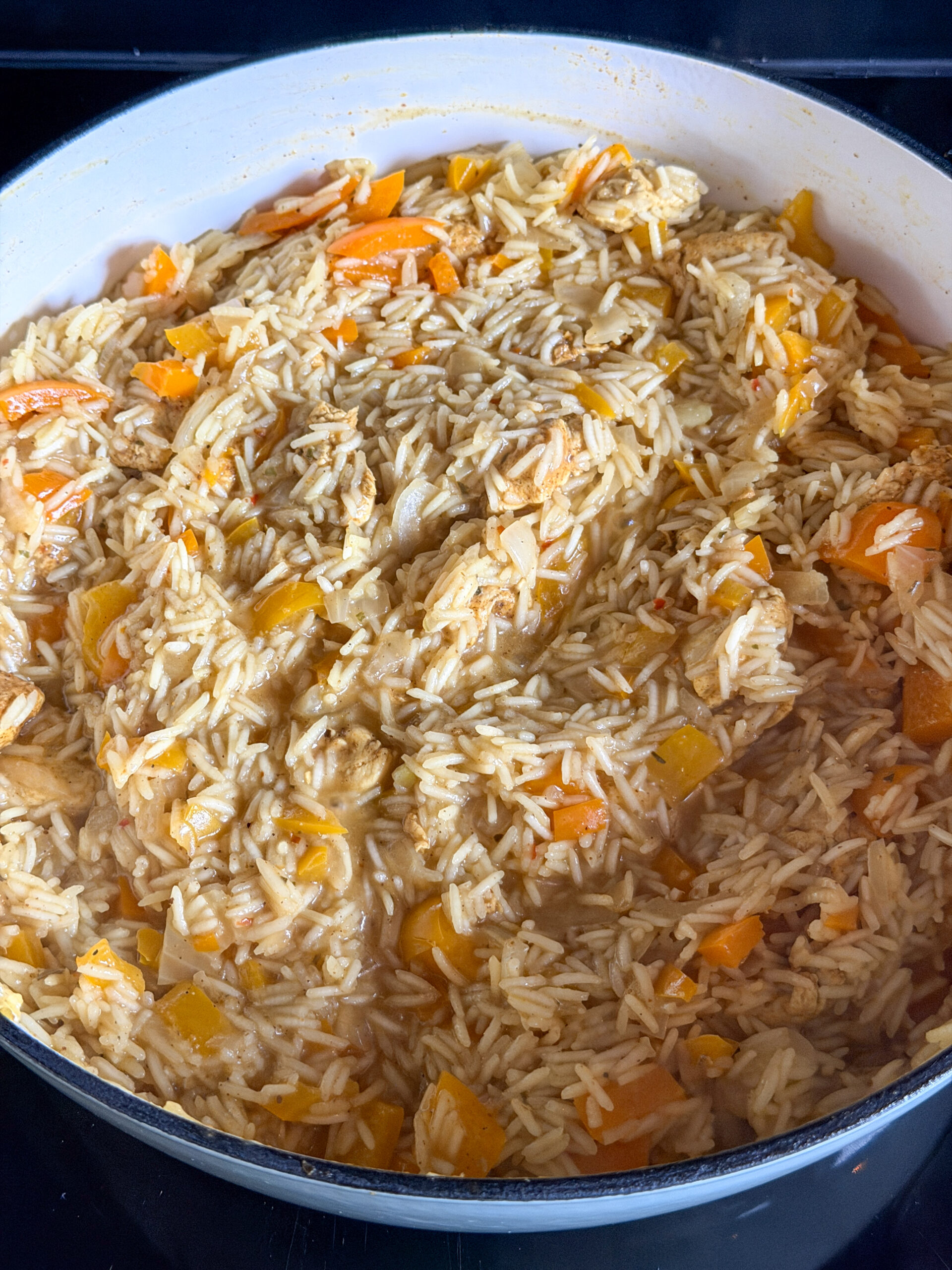 Rijst pruttelt met kip en paprika in het eenpansgerecht