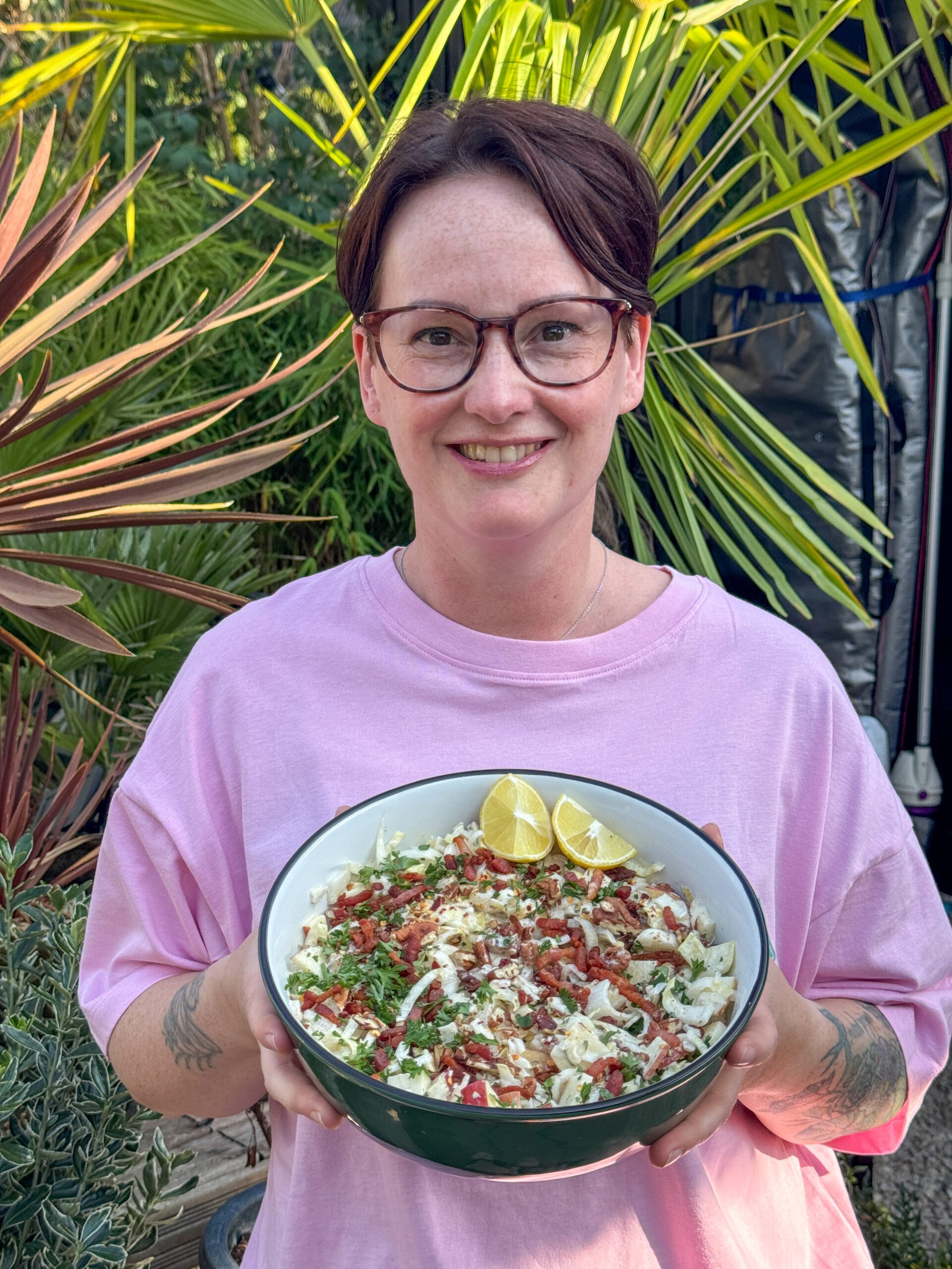 Marie Louise houdt een schaal met witlof salade met appel, spek en pecannoten vast