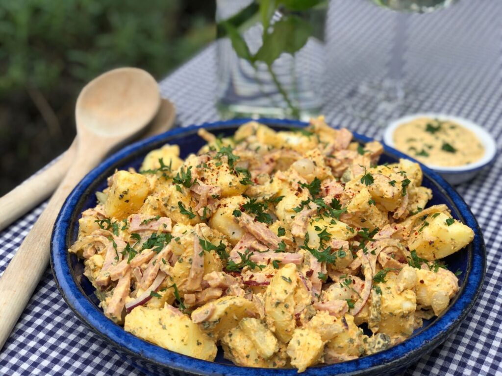 aardappelsalade met ham en kruidige dressing in schaal geserveerd