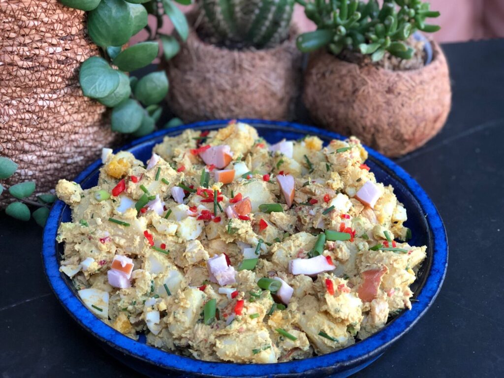 kerrie aardappelsalade met gerookte kip en ei in schaal geserveerd
