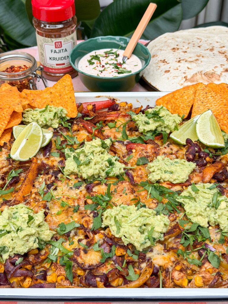 Fajita traybake met guacamole en tortilla chips geserveerd