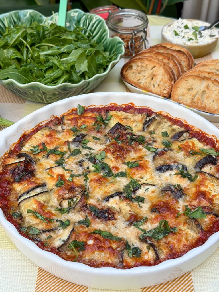 Close up van aubergine rolletjes in tomatensaus met gesmolten kaas en verse basilicum