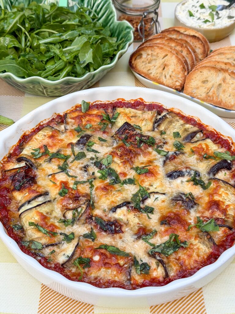 Aubergine rolletjes in tomatensaus geserveerd met geroosterde ciabatta, kruidenboter en rucola