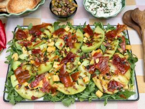 Salade met meloen en ham, gegrilde galia meloen, krokante prosciutto, blokjes kaas en pistachenoten