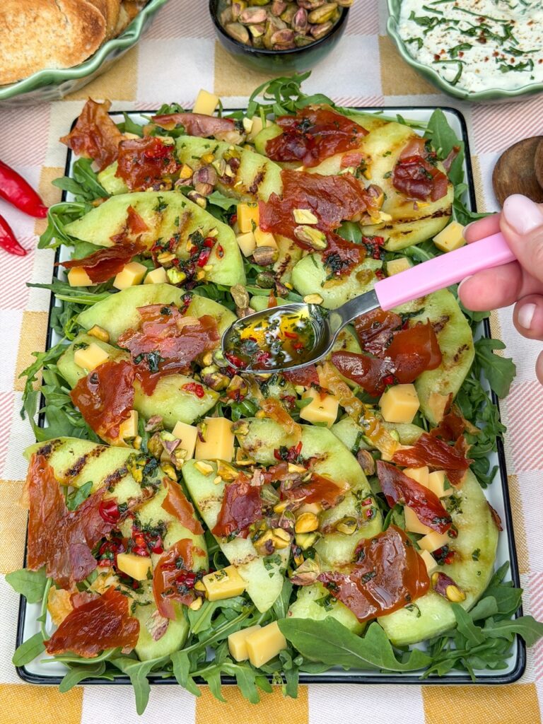 Dressing over salade met meloen en ham serveren