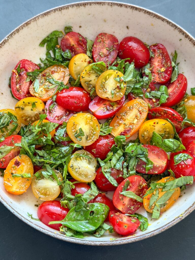 tomatensalade met gekleurde snoeptomaten, basilicum, olijfolie en gedroogde oregano voor pinsa caprese