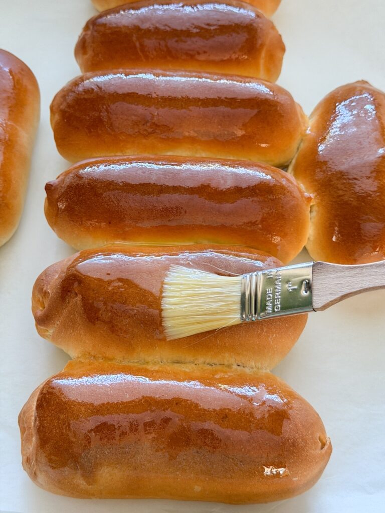 bestrijk de warme hotdog broodjes direct na het bakken met gesmolten boter