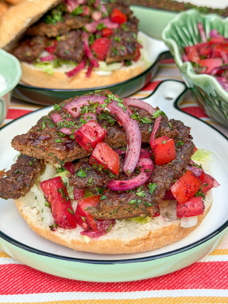 Broodje kebab belegd met Turkse sumak salade van rode ui, tomaat en komkommer