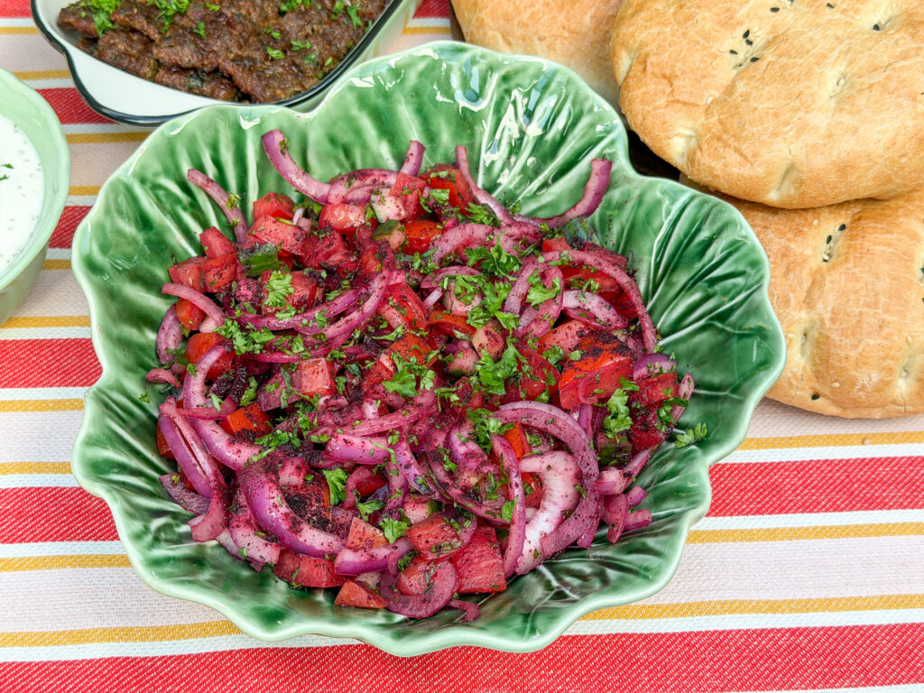 Turkse sumak salade recept met rode ui, tomaat, komkommer en peterselie in een groene schaal