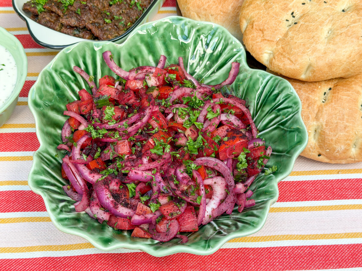 Turkse sumak salade recept met rode ui, tomaat, komkommer en peterselie in een groene schaal