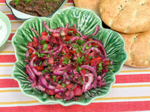 Turkse sumak salade recept met rode ui, tomaat, komkommer en peterselie in een groene schaal