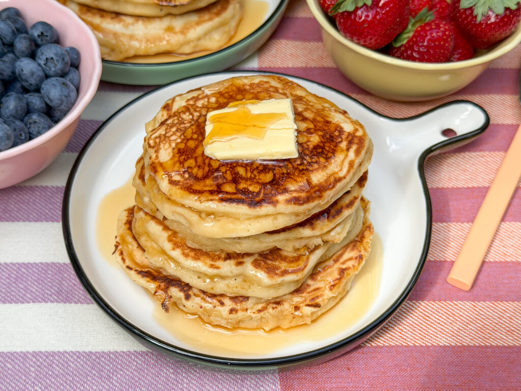 Luchtige American pancakes met roomboter en maple syrup op een bord