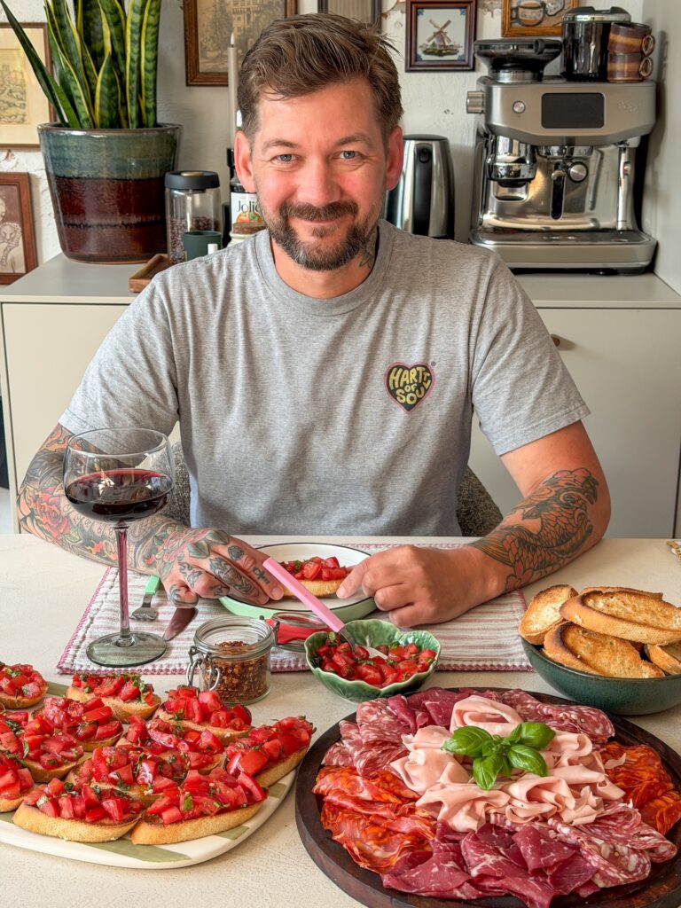 Jan Willem geniet van bruschetta met tomaat een schaal Italiaans beleg en een glas rode wijn