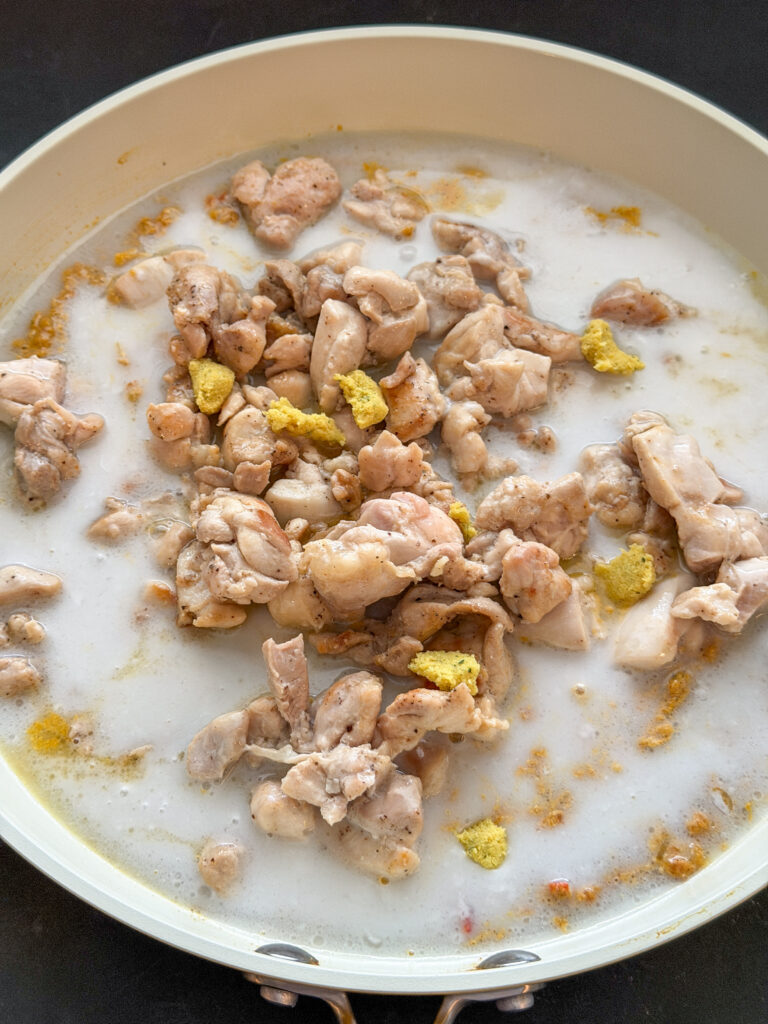 kippendij en kokosmelk in de pan met verkruimeld bouillonblokje voor kip kormasaus