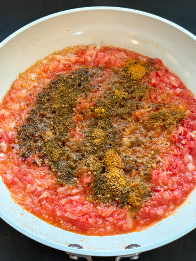 ui, geraspte tomaten en specerijen bakken als basis voor zelfgemaakte kip korma