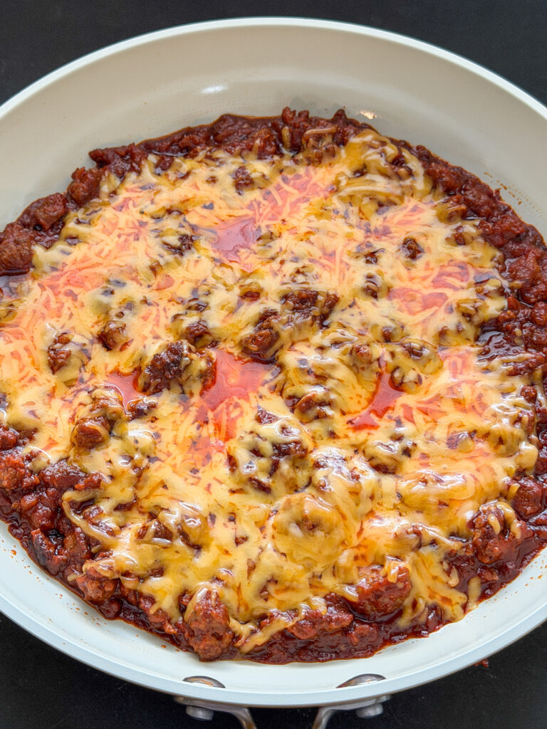 Gesmolten cheddar op de warme sloppy joe vulling in de pan