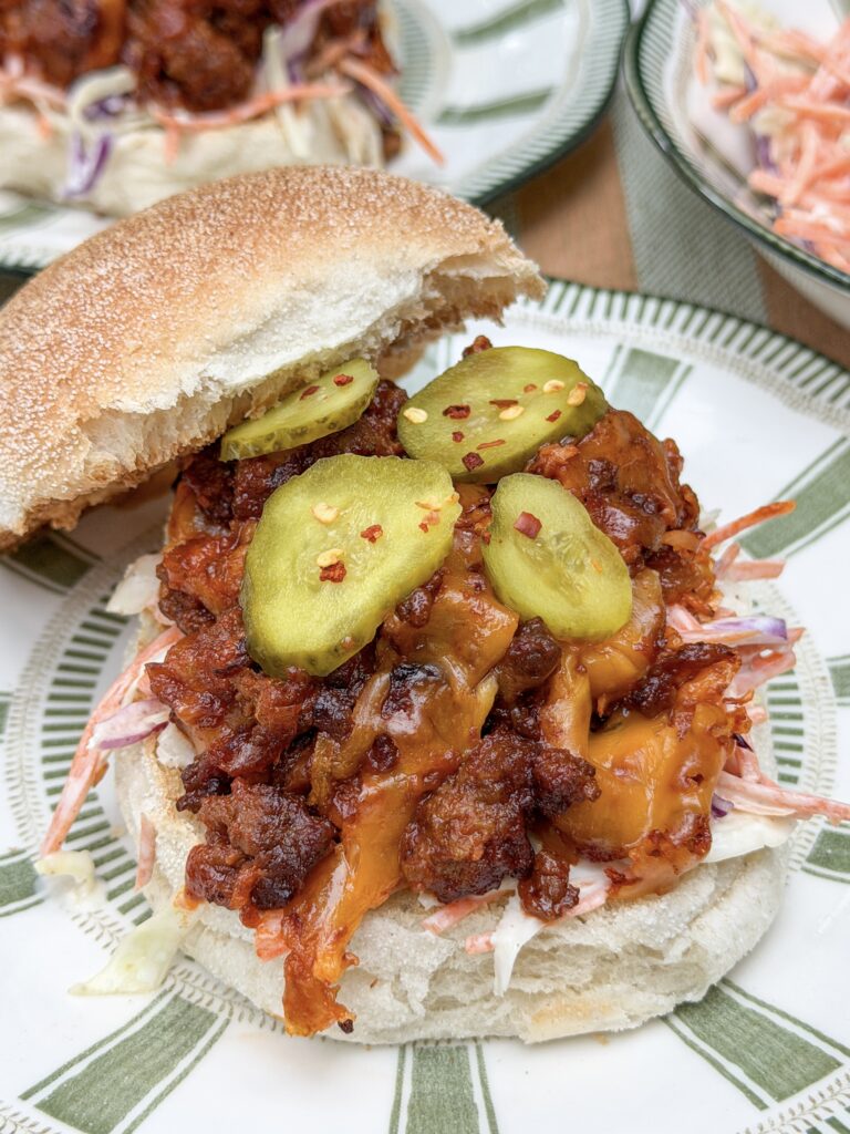 Sloppy joe met coleslaw, gesmolten cheddar en plakjes augurk op een zacht broodje