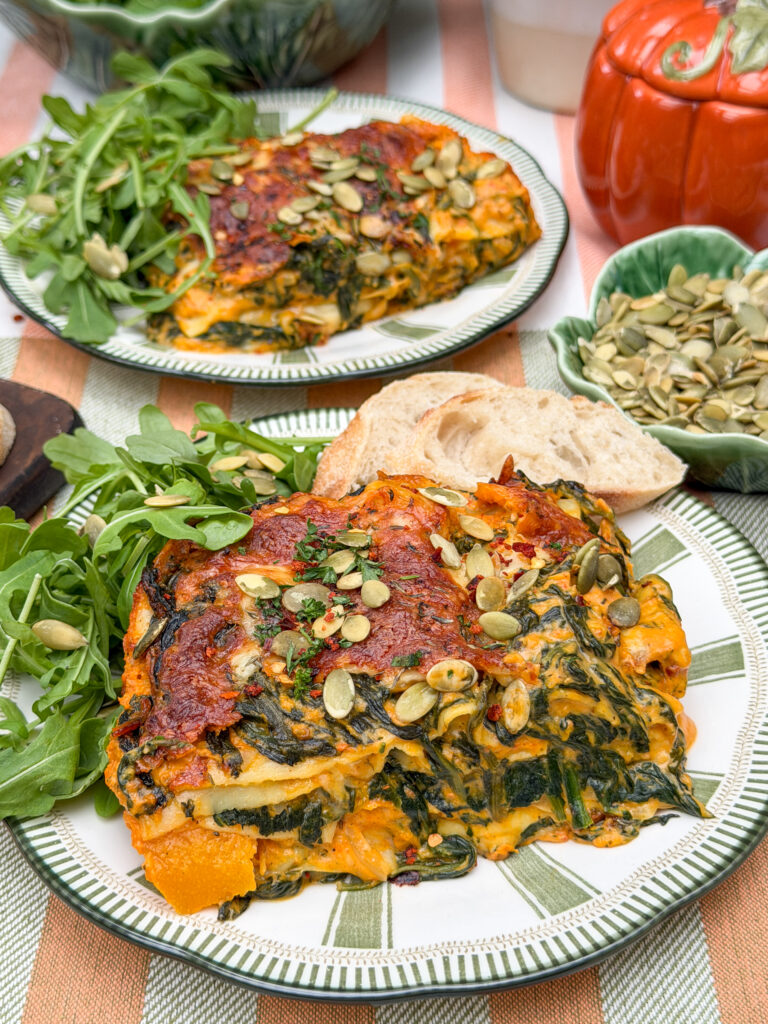 Romige pompoen lasagne met spinazie, geserveerd met rucola en stokbrood
