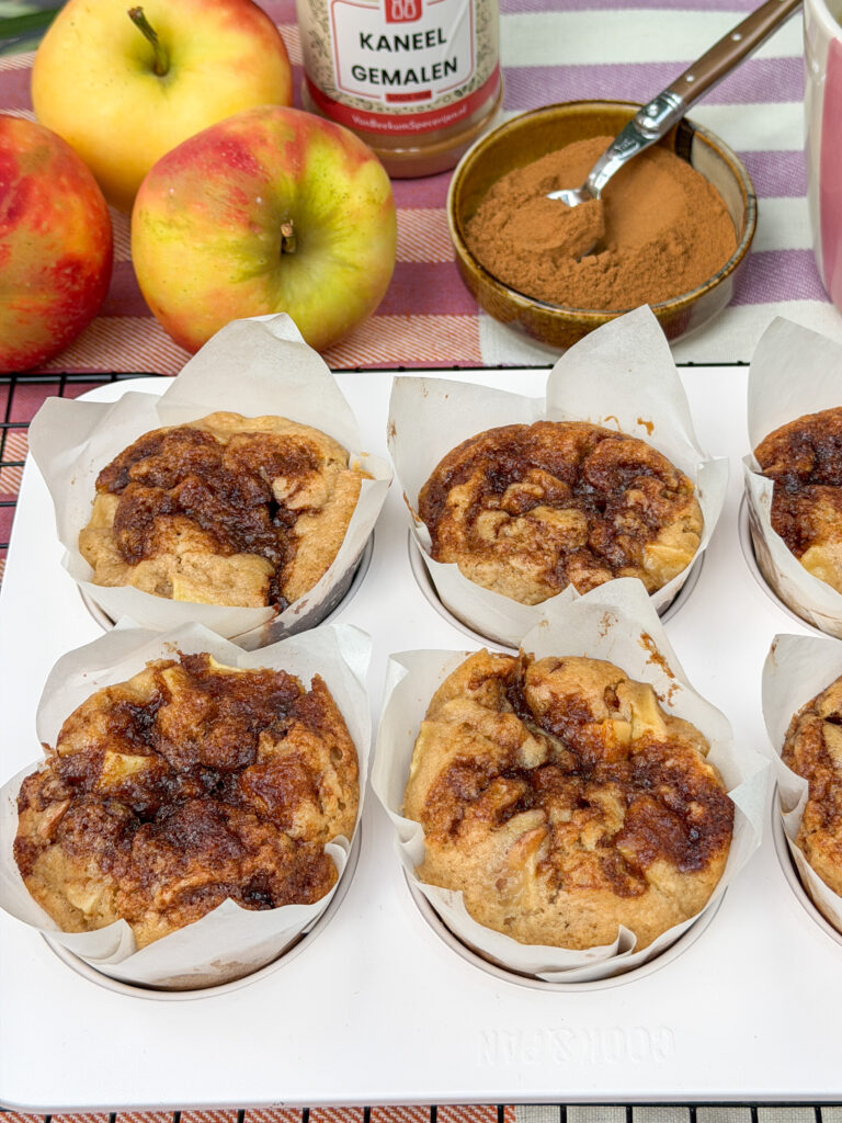 versgebakken appel kaneel muffins in hoge papieren vormpjes, gepresenteerd in een muffinblik