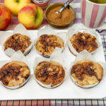 zes zelfgemaakte appel kaneel muffins met kaneelswirl, appels en kaneel op de achtergrond