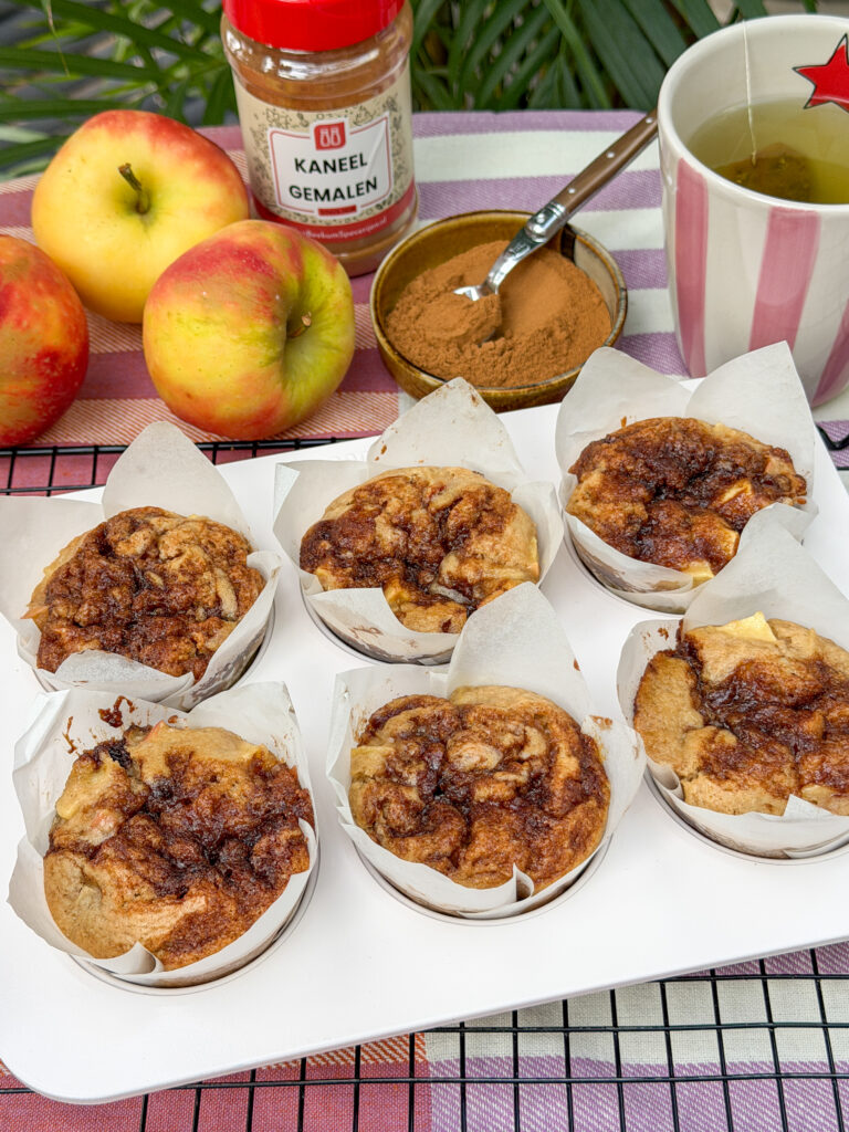 zes grote appel kaneel muffins met goudbruine kaneelswirl op een wit muffinblik