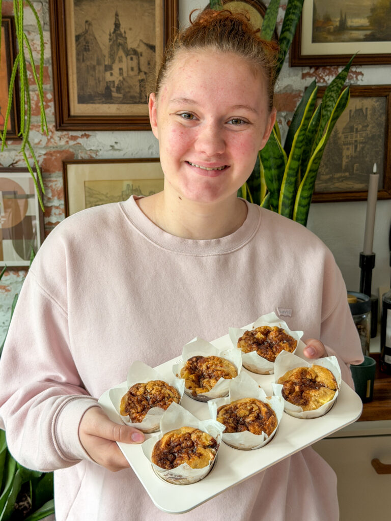 Amaranthe houdt muffinblik vast met zes zelfgemaakte muffins met appel en kaneel