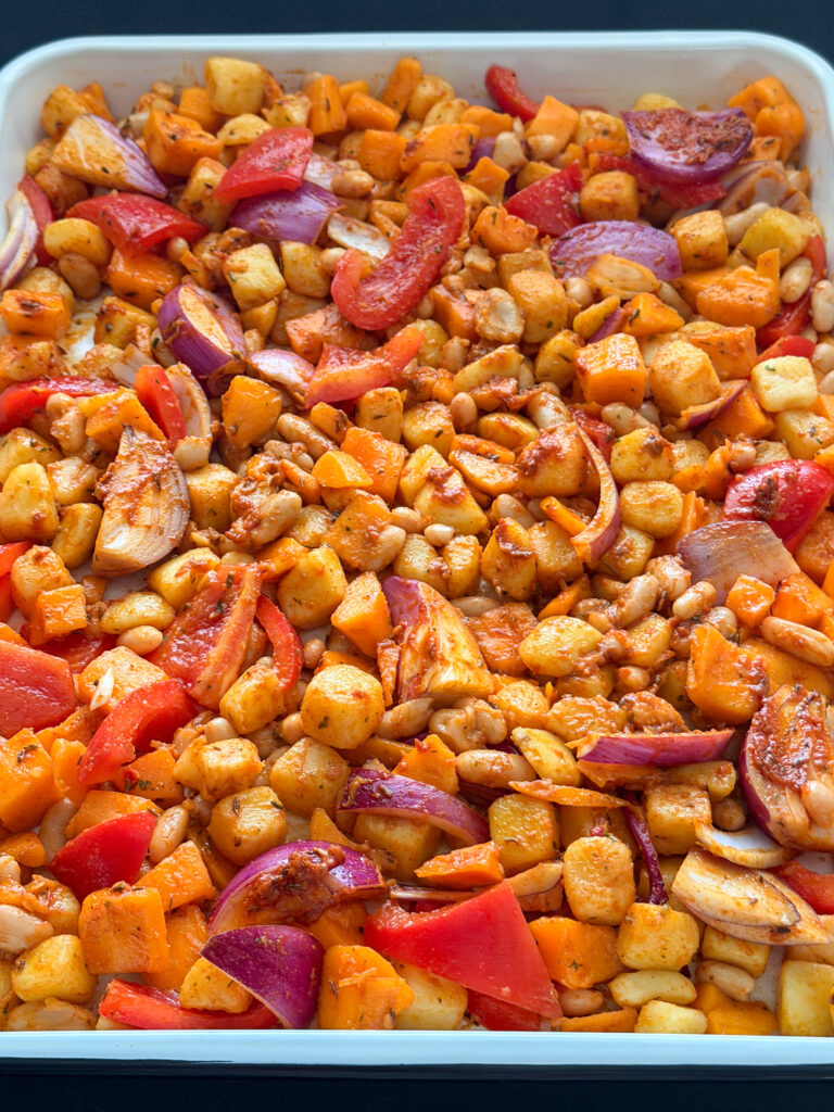 pompoenblokjes, krieltjes, rode ui, cannellinibonen en paprika met harissamarinade op een bakplaat